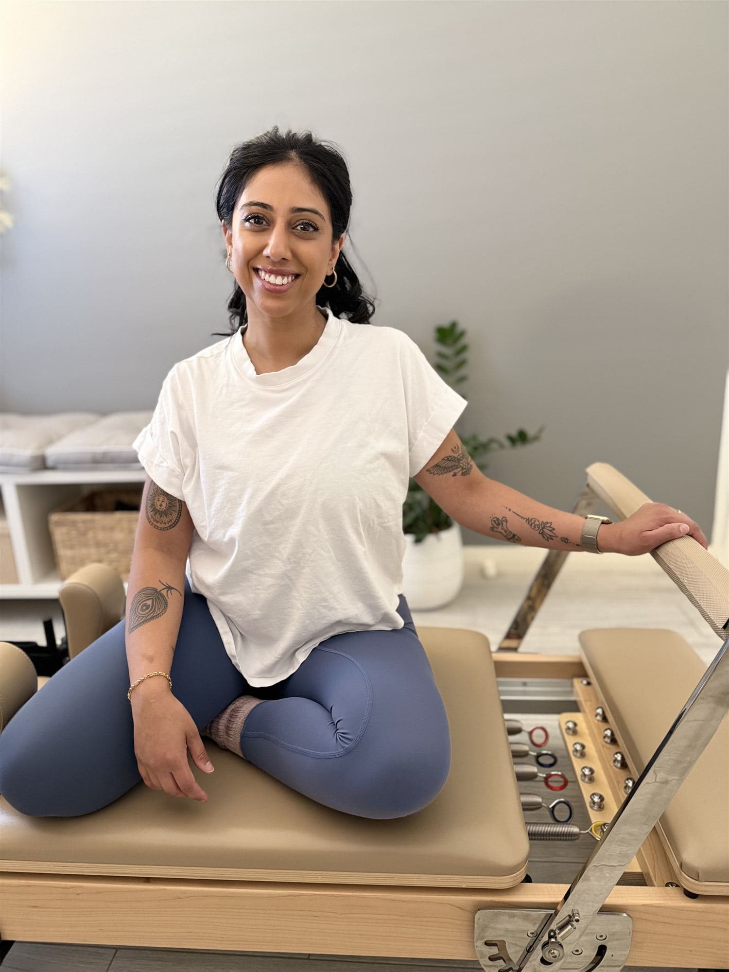 Pallavi, founder of Open Range Pilates, sitting on a reformer in her studio
